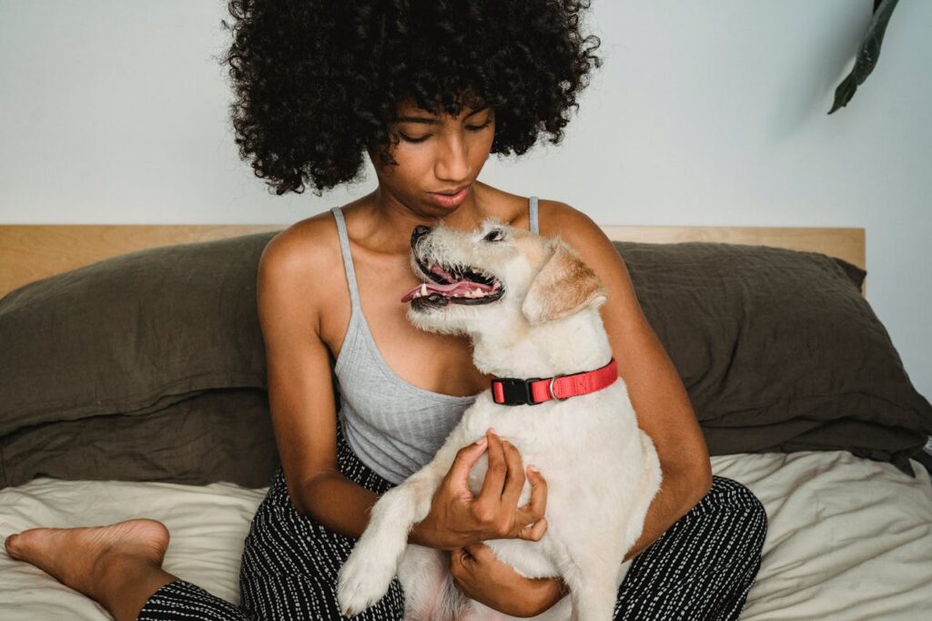 Black woman playing with dog in bedroom